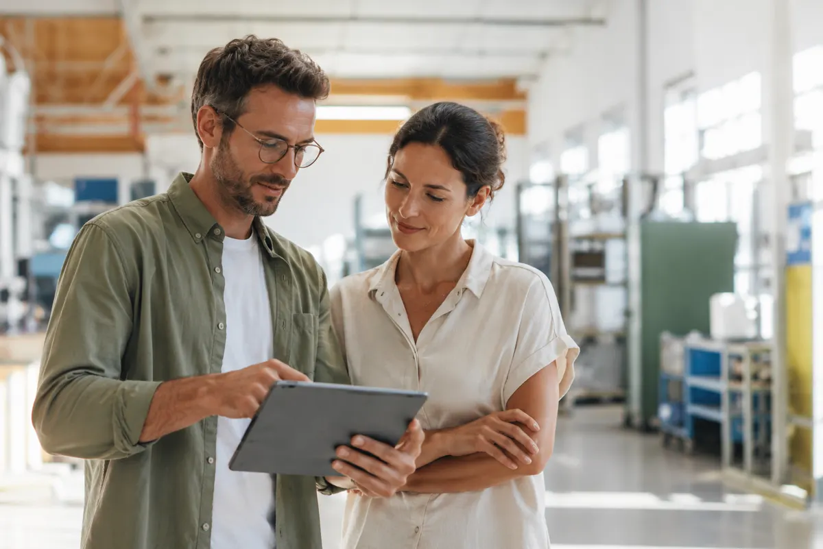 Deux ergonomes consultant une tablette dans un atelier
