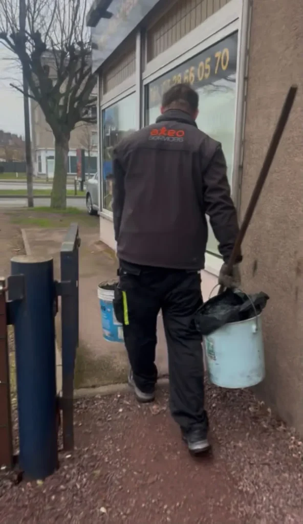 Agent d'entretien transportant des seaux de déchets