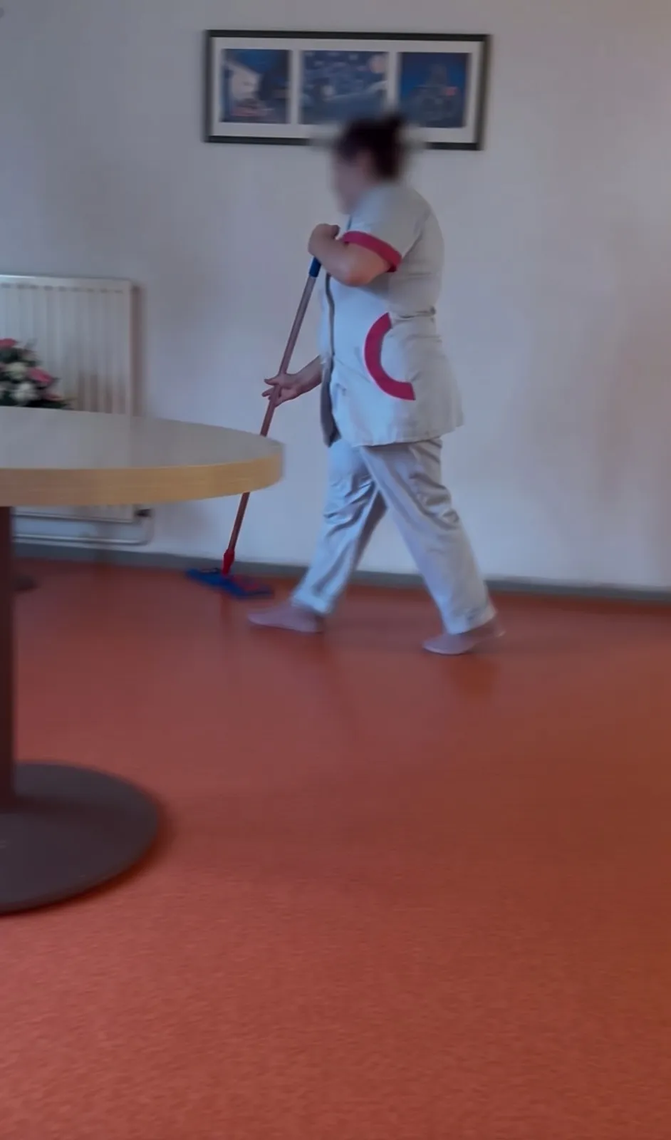 Agente d'entretien nettoyant le sol d'une salle commune
